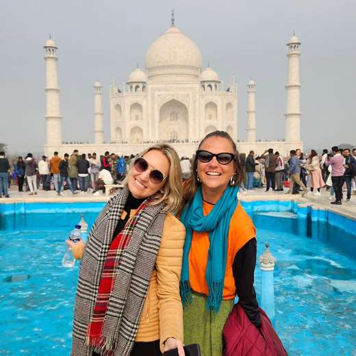 Two friends in scarves smiling in front of the Taj Mahal, India