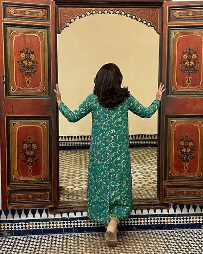 Traveler opening painted wooden doors onto a tiled courtyard in Marrakech